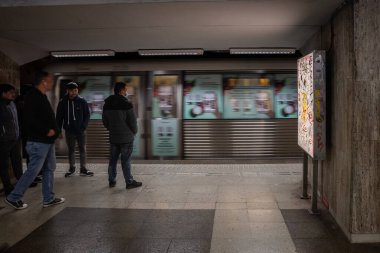 BUCHAREST, ROMANIA - 13 Mart 2023: Bükreş metro istasyonunu bekleyen ve hız bulanıklığıyla geçen insanlar için seçici bulanıklık. Metro, Romen başkentinin ana toplu taşımacılık bağlantısı.