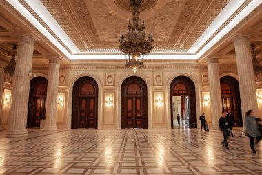 BÜKREŞ, ROMANIA - 13 Mart 2023: Ahşap kapılar üzerindeki seçici bulanıklık ve Romanya 'nın Bükreş' teki komünizm simgesi olan Romanya parlamentosunun içindeki bir salonun varlıklı tasarımı.