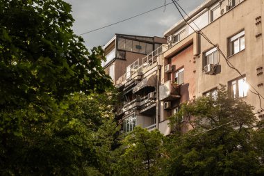 Gün batımında Belgrad şehir merkezinde, Stari Grad, Dorcol semtinde, eski gri cepheli, çürüyen çok katlı bir binanın ön cephesinde seçici bulanıklık.