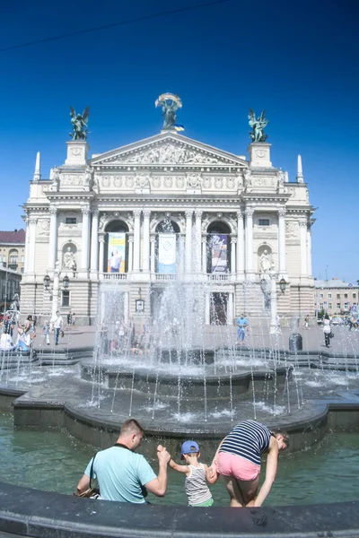 LVIV, UKRAINE - 11 Ağustos 2014: Ukraynalı bir aile, baba, anne ve çocuk, birleşik, Lviv Operası 'nın önünde duran seçici bulanıklık. Opera, bu Ukrayna şehrinin ana anıtıdır..