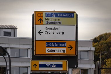 Almanya 'nın Wuppertal kentindeki bir Alman yol tabelasında seçici bulanıklık, Dortmund & Dusseldorf & küçük şehirlerine otoyol yönlerini gösterir: Mettmann, Sonnborn, Ronsdorf, Cronenberg, Katernberg.
