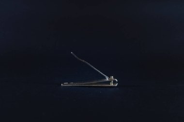 Siyah arka planda, koyu renkli metal tırnak makasındaki seçici bulanıklık. Tırnak makası, tırnak ve ayak tırnaklarını kesmek ve kesmek için kullanılan bir manikür aletidir..