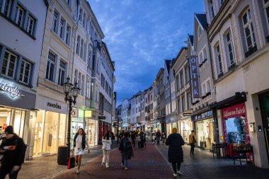 BONN, GERMANY - 11 NOVEMBER 2022: Sternstrasse 'de seçici bulanıklık, alacakaranlıkta Bonn' un ortaçağ ana caddesi, dükkanlar ve butiklerle bir yaya şehrinden geçen bir kalabalık.