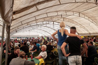 RUMA, SERBIA - 25 HAZİRAN 2023: Seçici bir bulanıklık, bir çift, erkek ve kadın, geleneksel bir Sırp restoranı ve barında duruyor, insanlar kutlama yaparken bira içerken.