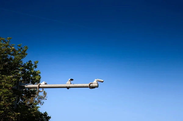 Selective blur on road traffic cameras, some CCTV cameras, used for observing and watching streets and traffic safety, in front of a blue sky. These CCTV cameras are used for public area safety.