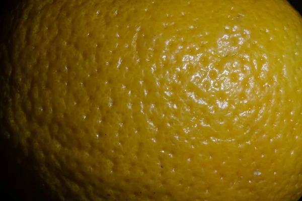 Selective blur on the peel of an orange skin with a focus on its texture, between Yellow and Orange, with dark shades. oranges are fruits part of the citrus group.