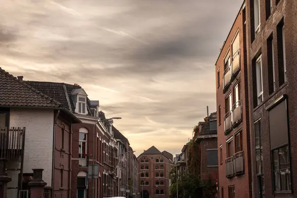Modern residential buildings and flats in the city suburbs of Maastricht, Netherlands of red brick, in an modern street with residential buildings. It\'s a typical Dutch street at dusk.