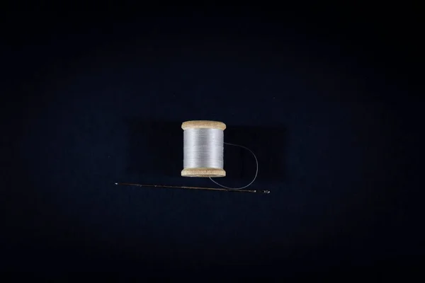 白い糸のリールと黒い背景に隔離された縫製針のスタジオショットに選択的なぼやき スプール またはリール 糸および針はDiy織物の縫うことおよび方法作成のために使用されます — ストック写真