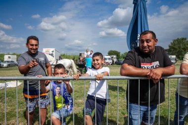 RUMA, SERBIA - 25 Haziran 2023: Roman bir ailenin portresi, Romani toplumundan iki baba ve iki çocuk, mutlu, fotoğrafçıya bakıyor.