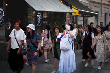 BELGRAD, SERBIA - 16 Temmuz 2023: Asyalı bir kadın için seçici bulanıklık, elinde akıllı telefon maskesi, Belgrad sokaklarında fotoğraf çeken bir turist, koronavirüs kovid 19 sağlık krizi.