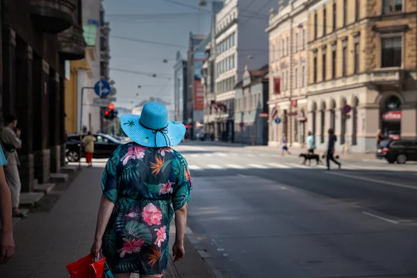 ラトビア August 2023 ラトビアのリガの通りで 後ろから見た青い帽子をかぶってバスを待っている女性の選択的なぼやき — ストック写真
