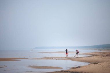 GARCIEMS, LATVIA - 26 AĞUSTOS 2023: Baltık Denizi 'nde, Letonya kıyılarında, Garciems' de deniz kenarında sörf yapmayı öğrenen iki genç adamın seçici bulanıklığı.