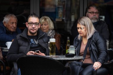 DORTMUND, ALMANY - NOVEMBER 5, 2022: İki kişi üzerinde bulanıklık, bira içen bir erkek ve Dortmund 'daki bir Alman bar ve kafesinin terasında tütün içen bir kadın.