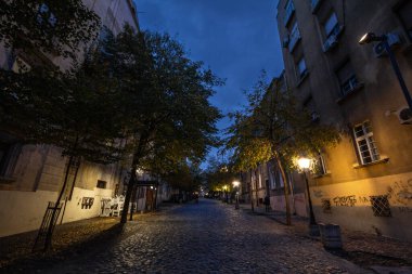 BELGRAD, SERBIA - NOVEMBER 12, 2019: Geceleyin Skadarlija Caddesi (Skadarlija olarak da bilinir), yanından geçen tipik kaldırım taşlı kafeleri, restoranları ve turistleriyle