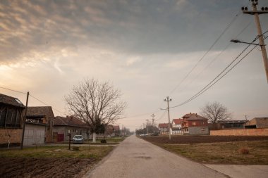 Sırbistan 'ın Voyvodina kentinin Banat bölgesine bağlı bir Sırp köyü olan Banatsko novo selo köyündeki tipik kırsal yol, akşam karanlığında. Sırbistan ve Orta Avrupa 'nın tipik bir kırsal manzarası..