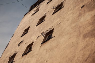 Şehir ortamında yenilenmek üzere olan bir binanın ön cephesi, bir sürü eski penceresi olan, çürümüş beton bir gri cephe..