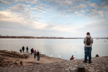 BELGRAD, SERBIA - 19 Şubat 2023: Zemun 'daki Tuna nehrinin kenarında ana su kanalı Zemunski kej veya Zemun Quay' de duran bir grup insanın seçici bulanıklığı.