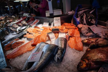 RIGA, LATVIA - 21 AĞUSTOS 2023: Bir balıkçı, bir balıkçı, bir balık tüccarı, Riga Central Market 'in bir tezgahında müşterilere balık ürünleri satan somon satışı için seçici bulanıklık.