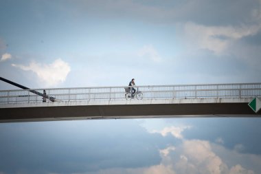 SREMSKA MITROVICA, SERBIA - 10 Haziran 2023: Sremska Mitrovica şehir merkezinde bisiklet süren adam, Bulutlu bir öğleden sonra, Sava Nehri üzerinde,.