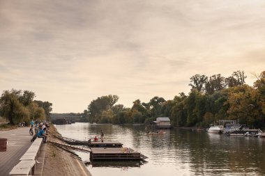 PANCEVO, SERBIA - 7 Ekim 2023: Tamis nehrinde, Pancevo Rıhtımı 'nda dubalarla oynayan çocuklar, sonbahar öğleden sonra alacakaranlığı sırasında. Pancevo banat içinde bir Sırp şehridir..