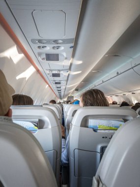 RIGA, LATVIA - 20 AĞUSTOS 2023: Baltık devletlerindeki Riga 'ya giden yolcularla dolu bir Airbus A220 planının iç kabini ve koltukları. AirBaltic, Letonya 'nın havayolu şirketi..