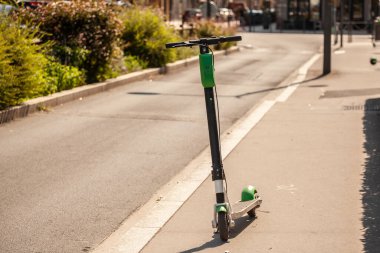 Kiralık siyah ve yeşil elektrikli scooter 'da seçici bulanıklık. Lyon, Fransa sokaklarında tek başına duruyor. Araç paylaşım alanında uzman bir teknoloji şirketine ait..