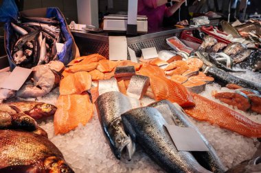 Selective blur on salmon for sale at a fishmonger, a fish merchant, selling fish products to clients at a stall of Centraltirgus, Riga Central market. clipart