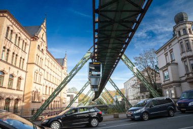 WUPPERTAL, GERMANY - 11 Kasım 2022: Wuppertal schwebebahn 'dan geçen trende seçici bulanıklık, şehrin ikonik süspansiyon demiryolu aşağıda trafik sıkışıklığı olan.