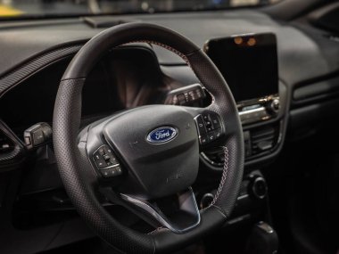 BELGRAD, SERBIA - 23 Mart 2024: Ford 'un direksiyon simidi, arka planda dokunmatik ekran. Ford Motor Company bir otomobil üreticisi ve bir Amerikan otomotiv şirketi..