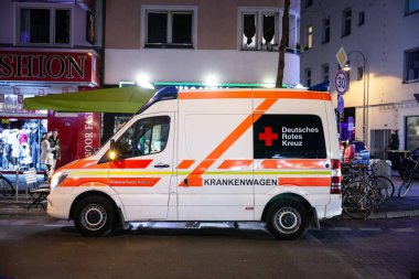 COLOGNE, GERMANY - NOVEMBER 12, 2022: Alman Kızıl Haç 'ından Alman ambulansı (krankenwagen), Deutsches Rotes Kreuz a van, gece kolonya üzerinde, acil müdahaleye hazır.