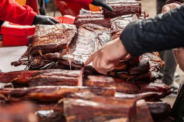 stock image Selective blur on blocks of slanina, a serbian bacon, made of dried cured pork smoked on the stand of countryside market of Serbia with hands buying some. It's a traditional meat product from Balkans.