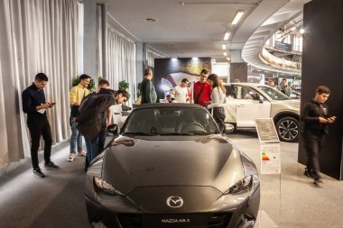 BELGRAD, SERBIA - 23 Mart 2024: Belgrad 'daki bir bayilikte Mazda MX5' i denetleyen müşteriler. Mazda MX5 üstü açık bir Japon spor arabasıdır..