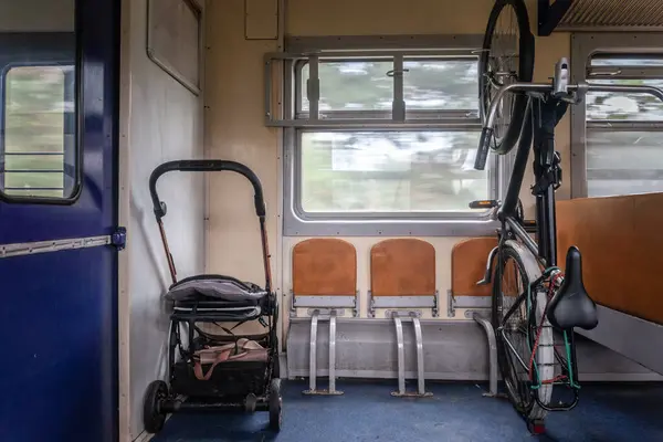 stock image Selective blur on a stroller for baby and toddler parked by a bicycle stored in an accessible compartment of a train of Latvian railways, in a specific storage facility designed for oversized vehicles.