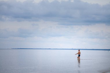 Letonya 'daki Jurmala Sahili' nde Baltık Denizi 'ne giren adam