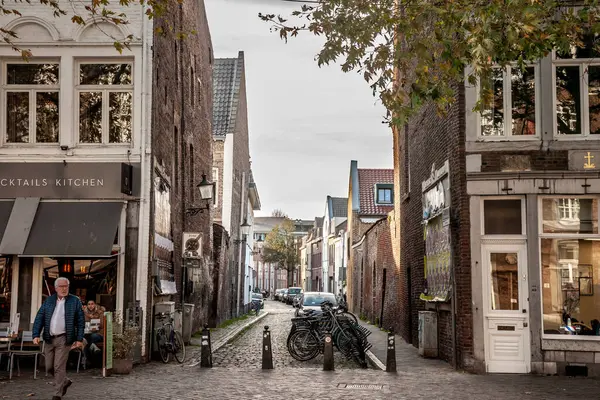 stock image MAASTRICHT, NETHERLANDS - NOVEMBER 10, 2022: Bicycles parked in a bike parking area on a street in Maastricht, Netherlands, in front of a pedestrian street of city center, known for its dutch urbanism.