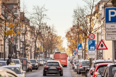 TROISDORF, GERMANY - 12 Kasım 2022: Troisdorf 'un tipik bir Alman banliyö sokağının panoraması park halindeki araçlar ve alacakaranlıkta geçen otobüsler.