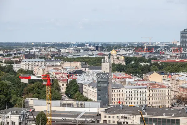 stock image RIGA, LATVIA - AUGUST 21, 2024: Aerial panorama of Riga city center with cranes of a construction site, illustrating urban development.