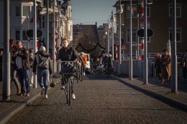 MAASTRICHT, NETHERLANDS - NOVEMBER 10, 2022: People biking on Sint Servaasbrug bridge in Maastricht city center. Netherlands are known for people using bicycle as transportation. clipart