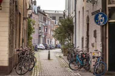 MAASTRICHT, NETHERLANDS - NOVEMBER 10, 2022: Bicycles parked in a bike parking area on a street in Maastricht, Netherlands, in front of a pedestrian street of city center, known for its dutch urbanism. clipart