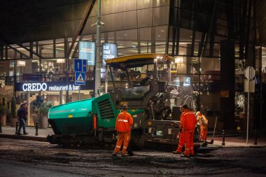 BELGRAD, SERBIA - 12 Şubat 2024: Sırbistan 'ın başkenti Belgrad' da bir gece inşaat projesi sırasında asfaltın yerini alan işçiler. Sahne kentsel yenilenme sürecini yakalıyor.