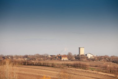 Panoramic view of a small village in Vojvodina, Serbia, surrounded by agricultural fields. The rural landscape highlights the region's agricultural heritage. clipart