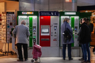 DÜKSELDORF, GERMANY - 7 Kasım 2022: Almanya 'daki Düsseldorf Hbf tren istasyonundaki otomatlardan tren bileti alan insanlar. Sahne, günlük şehir yaşamını ve toplu taşıma kullanımını yakalıyor.