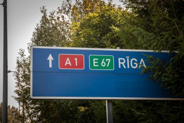 A1 ve Avrupa karayolu E67 üzerinden Riga 'ya giden yolları gösteren Letonya yol işareti, Avrupa karayolu numarasını kullanan e-yol ağında.