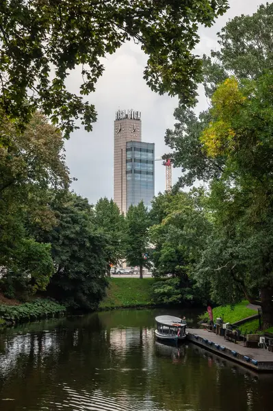 stock image RIGA, LATVIA - AUGUST 23, 2023: clocktower of Riga Train Station stands in front of Pilsetas Kanals (Riga City Canal) and Bastejkalns Park in front. called Pulkstenis, the clocktower is part of train station of Riga.