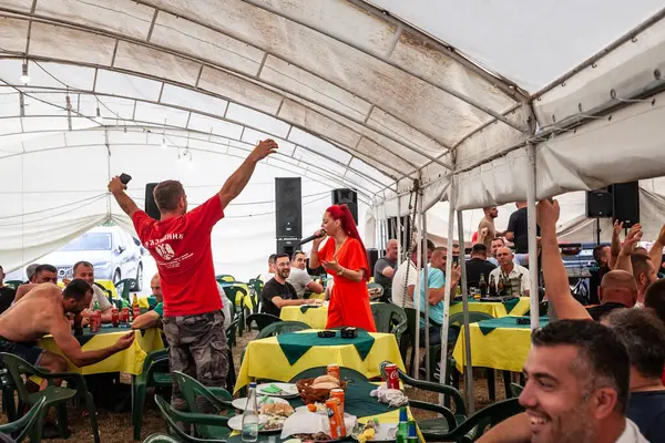 stock image KACAREVO, SERBIA - FEBRUARY 18, 2024: Woman, a serbian female singer performing in a kafana, a traditional serbian restaurant and bar, with people cheering, drinking alcohol happy & celebrating.