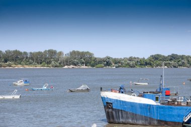 Boats moored along the Danube River in Belgrade with trees and nature in the background, of the river Dabube on Zemunski Kej, in Zemun, a suburb of Belgrade, Serbia, during an afternoon. clipart