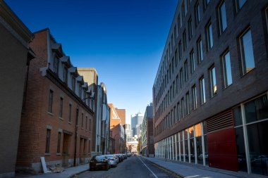 Montreal, Quebec 'teki iş gökdelenleri ve ofis binaları yakındaki bir sokaktan izleniyor. Binalar şehrin ekonomik ve finansal merkezini temsil ediyor ve modern Kanada mimarisini sembolize ediyor..