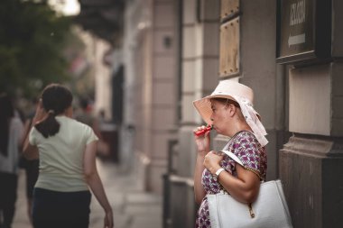 BELGRAD, SERBIA - 2 Ağustos 2024: Sırbistan 'ın başkenti Belgrad' da bir yaz günü e-sigarayla buharlaşan bir kadın. Puf, ya da e-sigara, tütün ve geleneksel sigaraya alternatiftir..