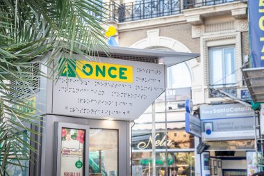 VALENCIA, SPAIN - OCTOBER 13, 2024: An ONCE sign on kiosk in Valencia. ONCE (Organizacin Nacional de Ciegos Espaoles) is Spanish charitable organization conducting lotteries to support blind people clipart