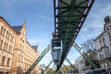 A train traverses the Wuppertal Schwebebahn, the iconic suspension railway of Wuppertal, Germany. This unique form of transportation is a hallmark of the city and a remarkable feat of engineering. clipart